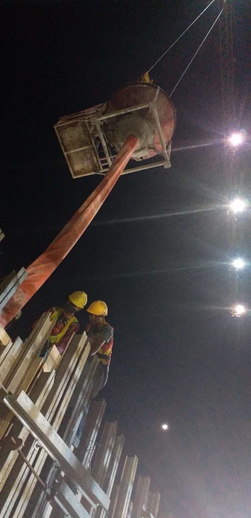 Workers operating a concrete vibrator during the concrete pouring of the retaining wall